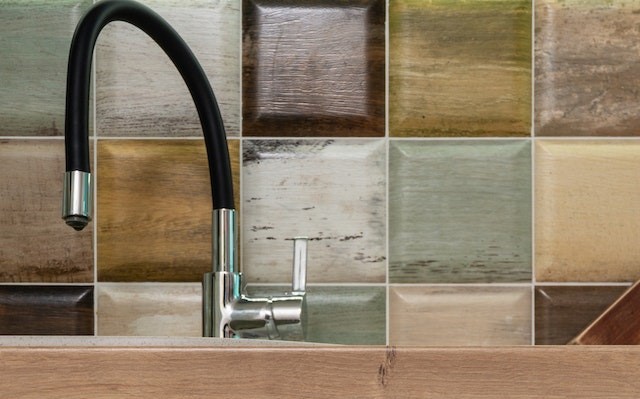 The tap of a kitchen sink with a colorful backsplash.