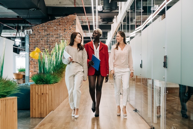 three women walking through an office space