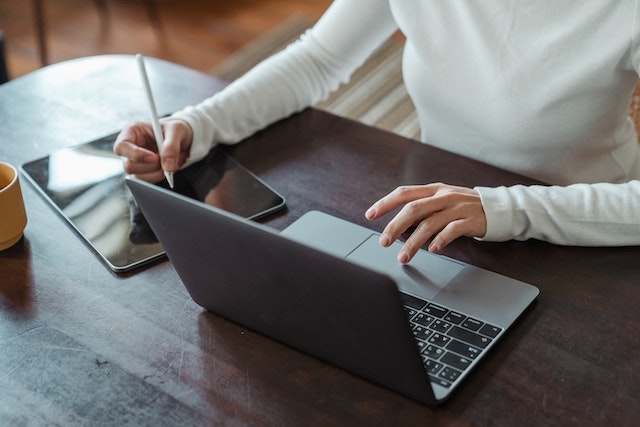 olympic-property-manager-sitting-at-desk-on-laptop-writing-notes